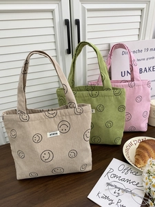 Three corduroy smiley face tote bags in beige, green, and pink colors with top handles