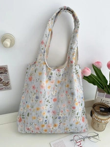 Détail de la broderie florale sur un sac cabas en toile bleu clair suspendu au mur
