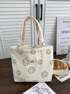 Close-up of cream corduroy tote bag with smiley face patterns and brand tag