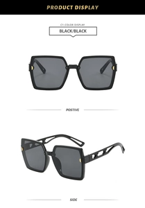 Vue détaillée des lunettes de soleil carrées noires avec détails dorés et branches ajourées