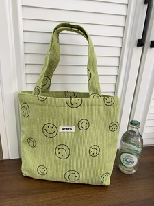 Close-up of light green corduroy fabric showing smile prints and soft textile texture