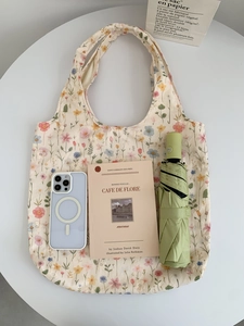 Détail du sac en toile brodé de fleurs montrant l'espace pour téléphone et parapluie