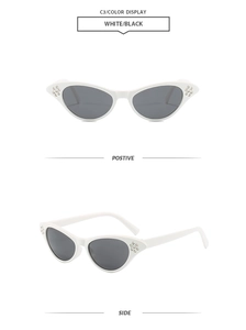 Detail view of white cat-eye sunglasses with rhinestone studs and dark lenses