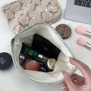 Detail of floral relief toiletry bags showing internal capacity and cream jacquard texture