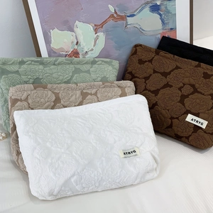 Detailed view of the 3D rose relief fabric texture on the elegant cosmetic bag set