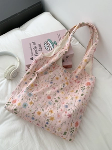 Gros plan détaillé de la broderie florale sur un sac cabas rose avec livre et casque