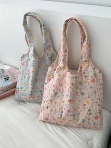 Détail de la broderie florale sur des sacs en toile de couleurs rose et bleu pastel