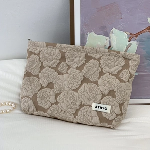 Detail of vintage jacquard makeup bag with rose relief texture on white linen