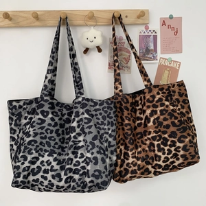 Detail of gray and brown leopard print canvas tote bags hanging on a wooden hook