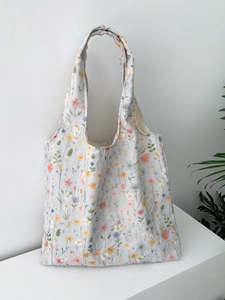 Détail de la broderie florale sur sac cabas en toile bleu clair avec fond minimaliste blanc