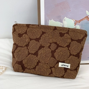 Detailed close-up of dark brown rose embossed jacquard fabric on a makeup pouch
