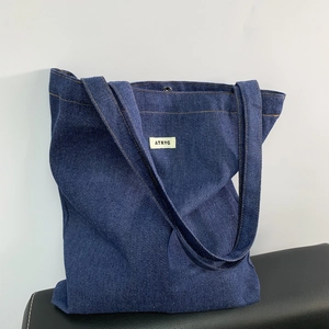 Detailed view of dark blue denim tote bag with magnetic clasp and ATRYG brand tag