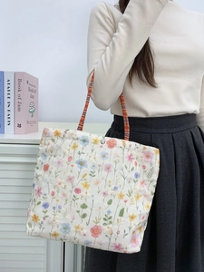 Floral embroidered canvas bucket bag with colorful flowers and woven shoulder strap