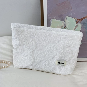Close-up of white embossed rose texture on fabric cosmetic bag with ATRYG label