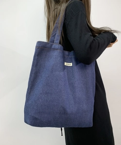Detailed side view of a large navy denim tote bag with ATRYG label on shoulder