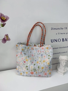 Close-up of floral canvas tote bag featuring orange woven handles and snap closure detail