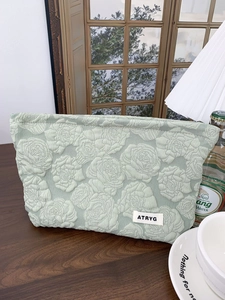 Macro shot of mint green fabric cosmetic bag with embossed rose texture and brand label