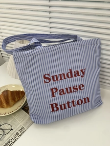 Détail du sac cabas en toile rayée bleue et blanche avec texte Sunday Pause Button rouge