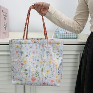 Detailed close-up of a floral embroidered canvas bucket bag with a woven handle and silver snap button