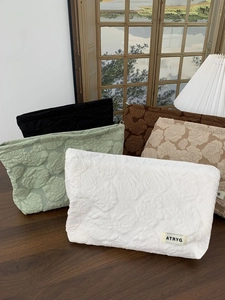 Detailed close-up of quilted rose embossed fabric bags with small minimalist logo labels