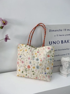 Detailed close-up of a floral canvas bucket bag with colorful embroidery and woven rope handles