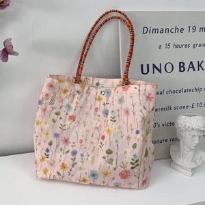Close-up of floral embroidery detail and woven rope handle on pink canvas bucket bag