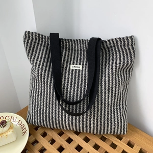 Macro detail of black and white herringbone woven tote bag with ATRYG brand label
