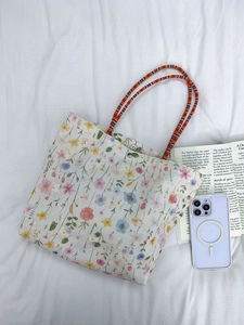 Close-up of floral canvas tote bag with orange rope handles and metal magnetic closure