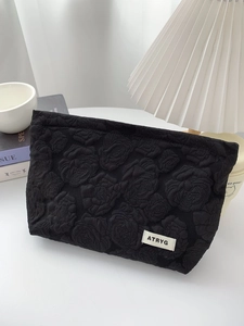 Minimalist black rose embossed fabric makeup bag with large capacity in a cozy setup