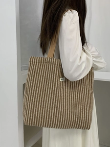 Detailed close-up of large herringbone tote bag with woven handles and brand label