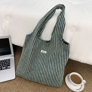 Flat lay of striped knit tote bag on rug with laptop and coffee, showing texture detail