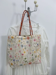 Detailed view of floral canvas tote bag with colorful striped woven handles and magnetic clasp