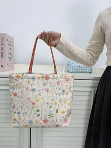 Close-up of floral embroidered canvas tote bag with orange handles and magnetic clasp