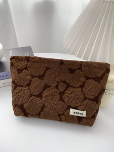 Brown jacquard storage bag with rose embossment and top zipper for makeup and toiletries