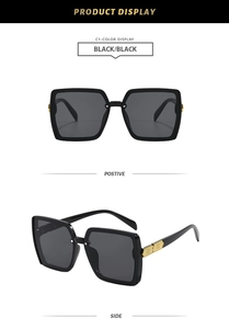 Detail view of square black sunglasses featuring elegant gold H-shaped metal hinges