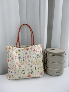 Detailed view of floral canvas tote with orange woven handles and silver snap closure