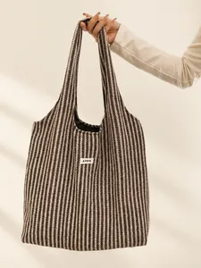 Detail of herringbone knit tote bag featuring premium woven texture and a brand label