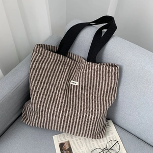 Detail of herringbone wool fabric and woven handles on a stylish office tote bag