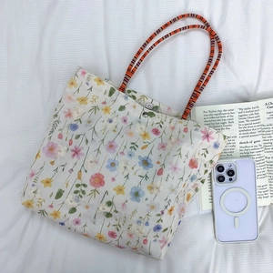 Detailed top view of embroidered floral canvas tote bag with magnetic snap and colorful straps