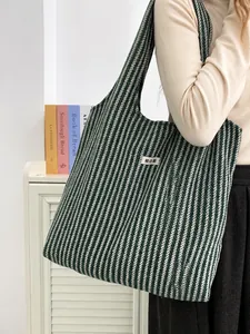 Close-up of a green herringbone wool tote bag worn over the shoulder by a model