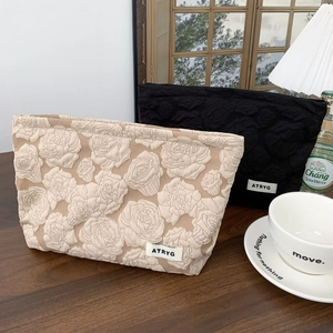 Close-up of dual-tone rose embossed fabric makeup bags in minimalist cream and black