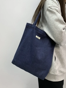 Close-up of large blue denim tote bag with white ATRYG woven label for daily commute