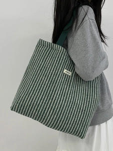 Detail of green herringbone wool tote with Atryg label and green shoulder strap