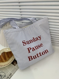 Sac fourre-tout en toile à rayures bleues et blanches avec lettrage rouge sur table