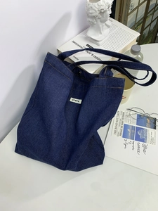 Detail of blue denim tote bag with ATRYG label on a minimalist aesthetic desktop