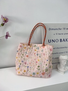 Detail of pink canvas tote bag featuring floral embroidery and woven handles in setting