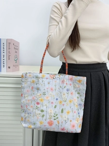 Detailed embroidery of colorful floral patterns on a canvas tote bag with metal buckle