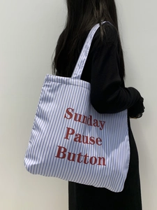 Détail du grand sac cabas en toile à rayures bleues avec texte rouge sur le côté
