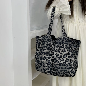 Detailed macro view of high-capacity leopard print canvas tote bag with wide shoulder strap