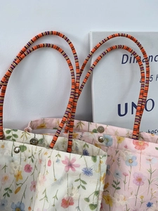 Detail of floral embroidery canvas tote bag with woven handles and metal snap closure